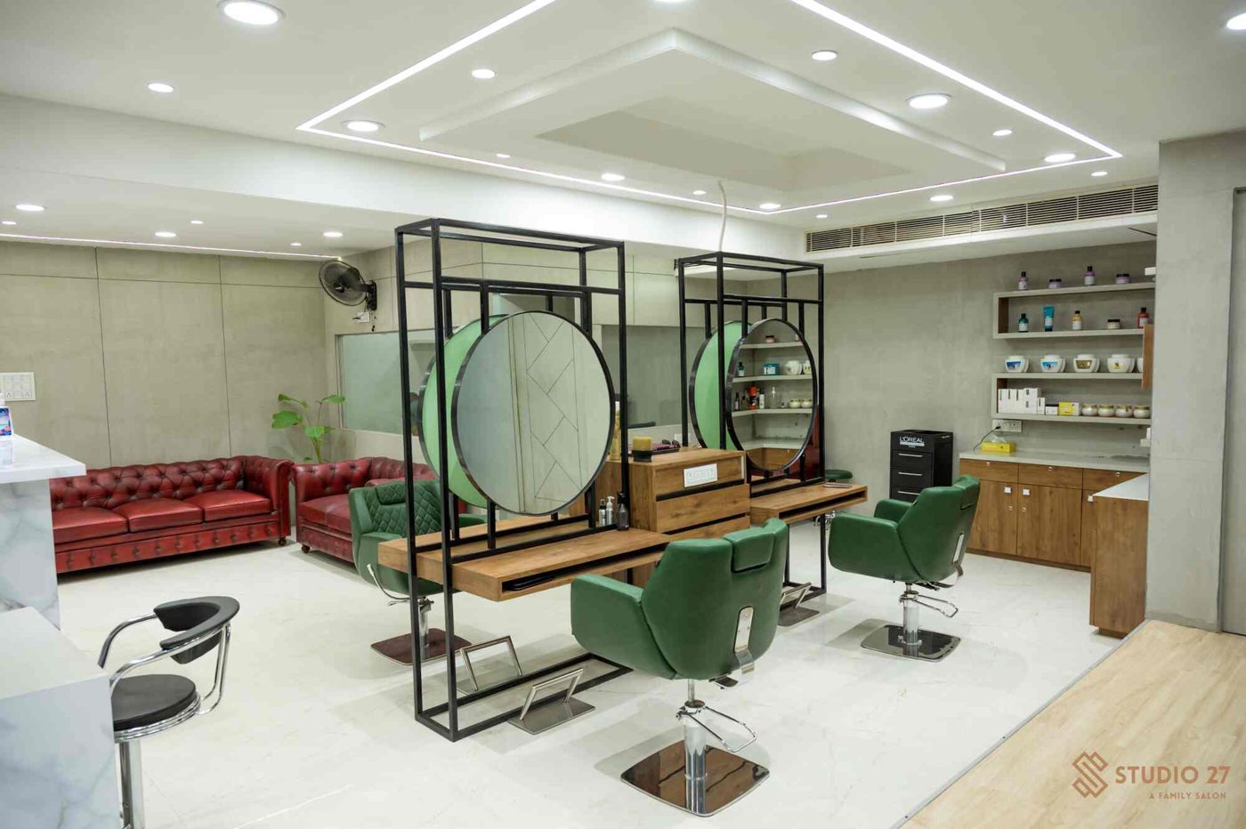 The Studio 27 floor with green chairs, round mirrors and a red chesterfield waiting sofa