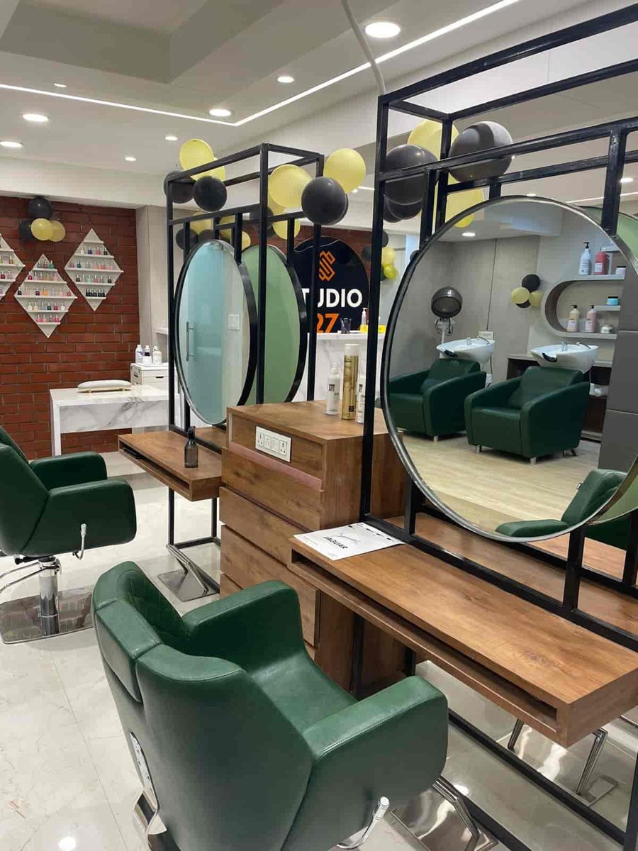 Round mirrors and forest-green styling chairs inside Studio 27, Bhopal