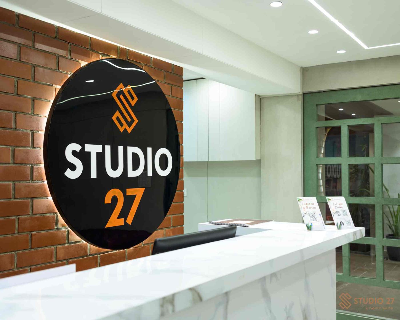 The lit Studio 27 sign on a brick wall